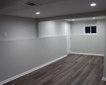 An example of a beautiful well done basement remodel. The walls are painted, the ceiling has aesthetically pleasing lighting, and wood floors were aded.