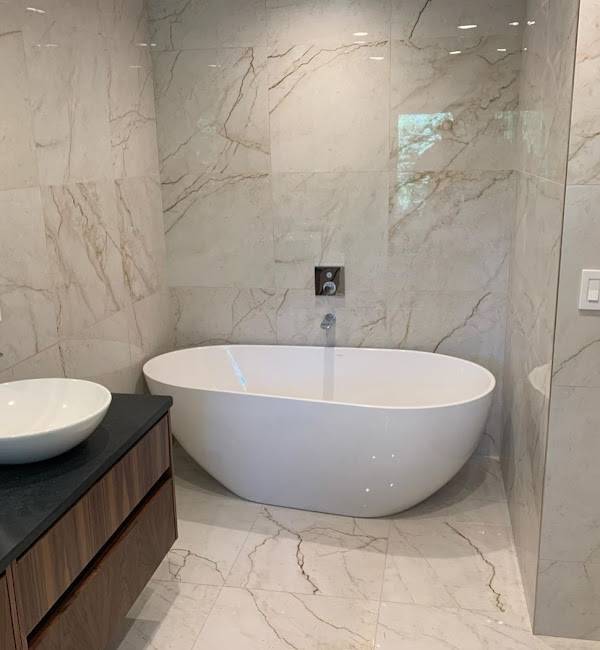 A modern and royal refinish of the bathroom adding a tub and other aesthetically pleasing changes such as the counter top having a wooden finish and a black countertop.