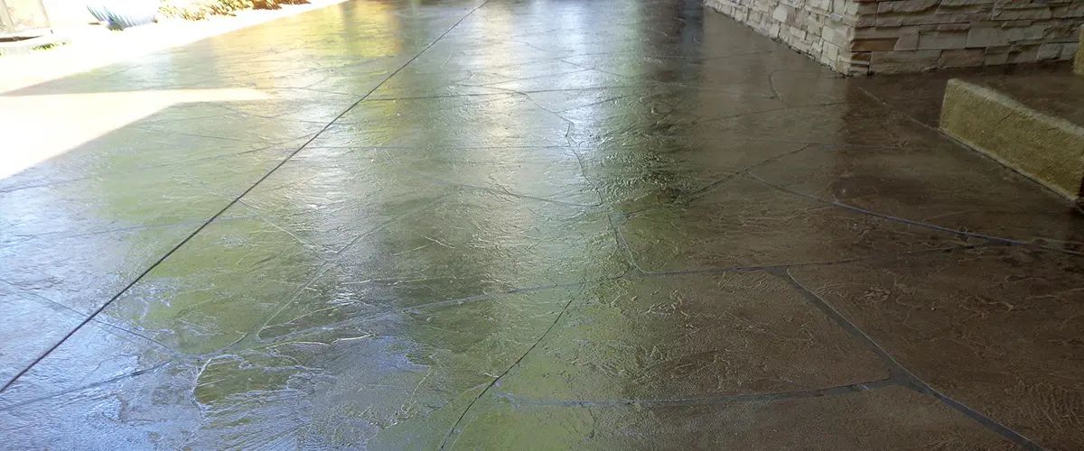 Stamped and stained concrete walkway beside stone wall