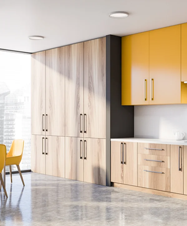 Modern kitchen remodeling project featuring yellow upper cabinets, light wood lower cabinets, sleek white countertops, stainless steel fixtures, and abundant natural lighting, crafted with expert detail.