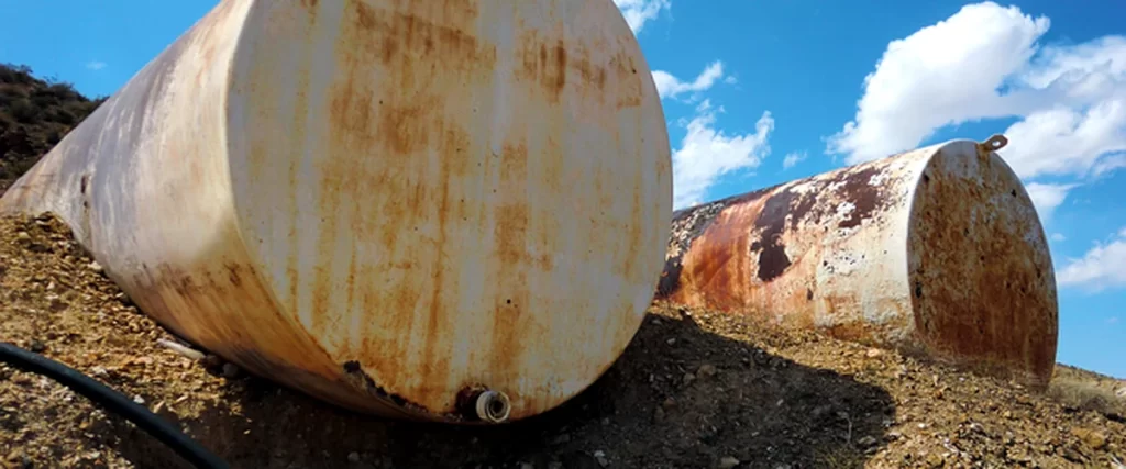 hidden oil tanks middletown colts neck nj home remodeling rusted steel oil tanks partially buried in rocky terrain under blue sky