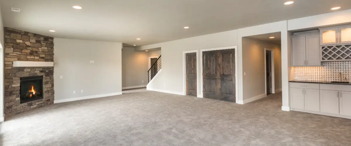 A spacious basement featuring a fireplace, adjacent to a modern kitchen