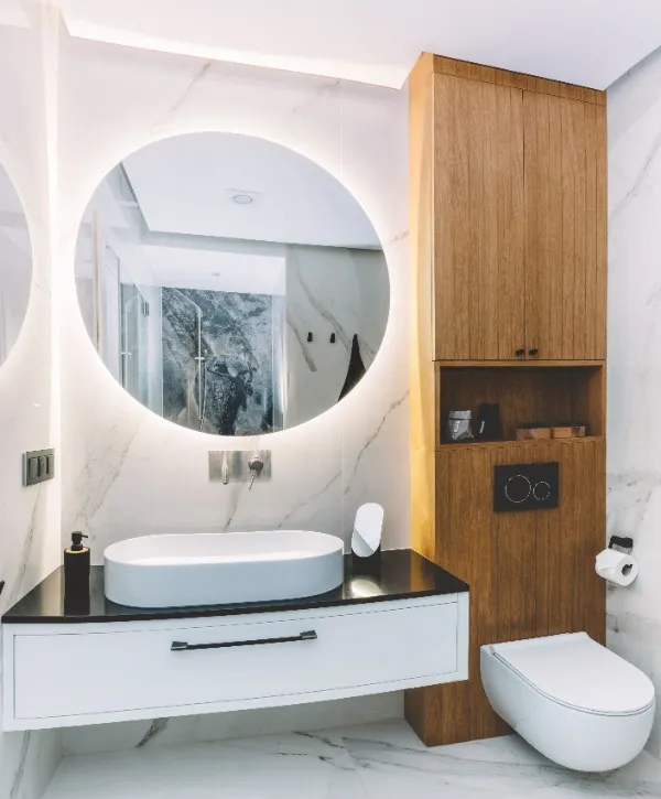 Sleek bathroom design with marble walls and a prominent round mirror, creating a spacious and modern look