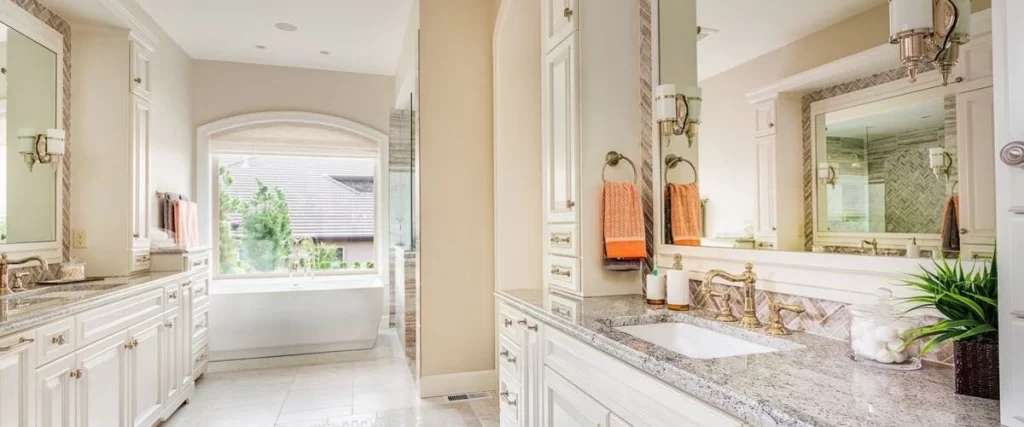 Bright and airy master bath design with extensive white cabinetry, speckled granite counters, ornate mirrors, and ample natural light