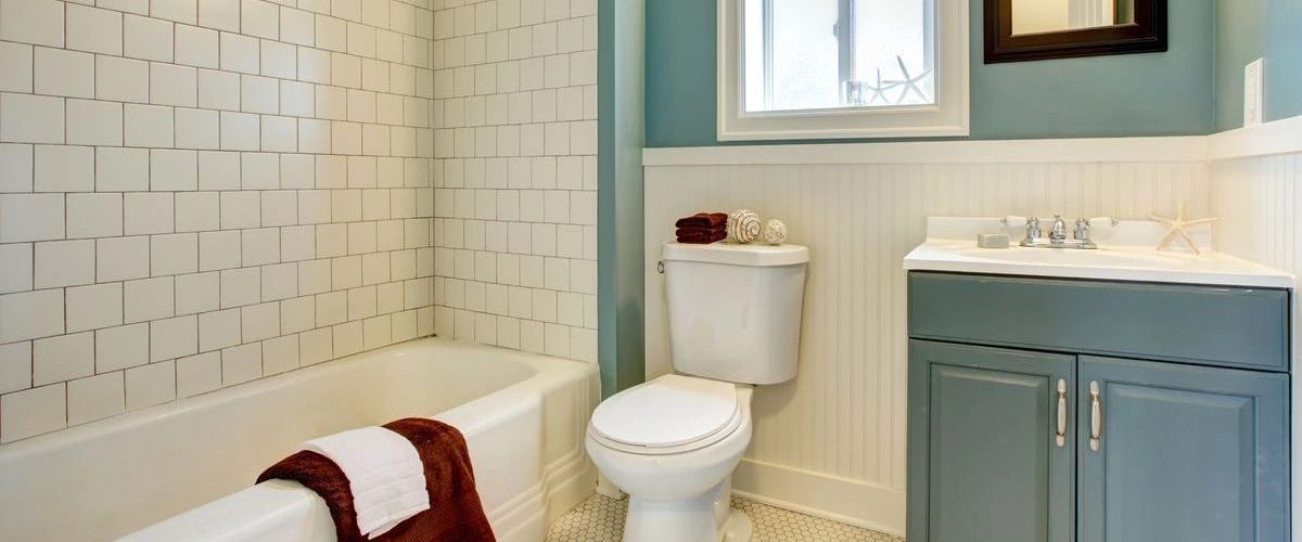 Contemporary bathroom corner featuring a floating light-wood vanity, a white ceramic vessel sink, and a large circular mirror on a neutral wall.