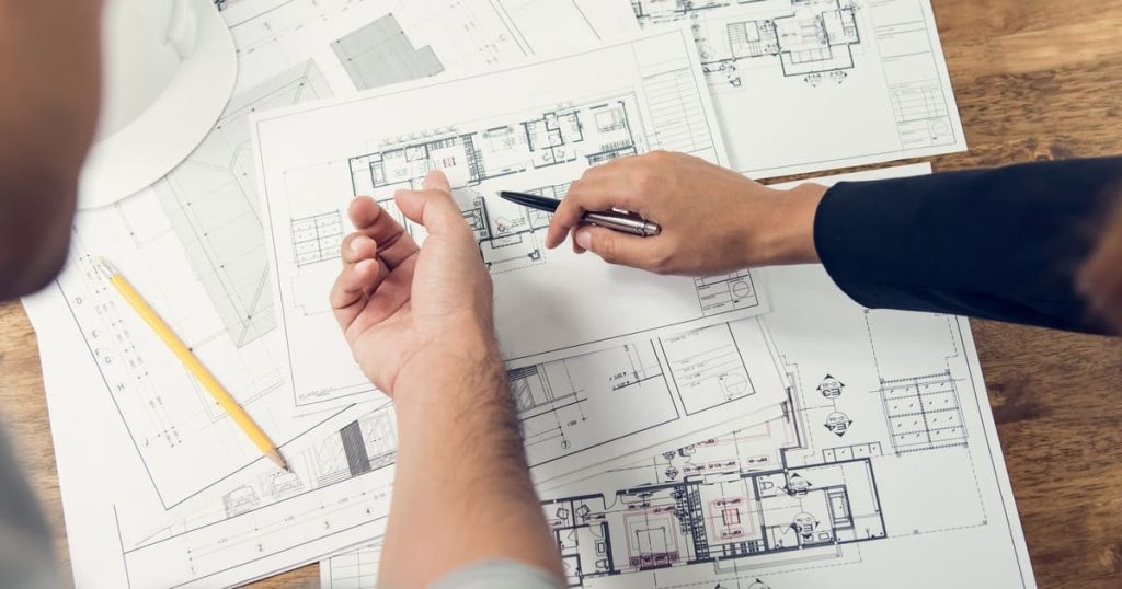 An architect pointing to specific details on Englishtown zoning codes blueprints during a project planning session.
