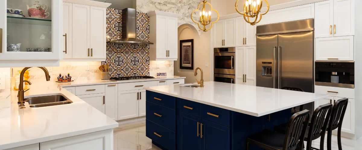 Spacious kitchen with white perimeter cabinets, a navy blue center island, gold hardware, and a decorative tile backsplash.