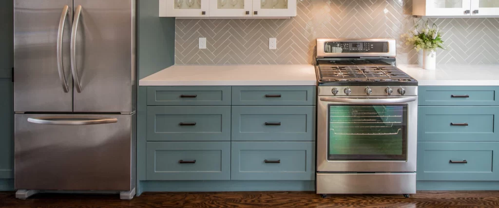A modern kitchen featuring teal shaker cabinets and high-end stainless steel appliances designed for a quiet home and reduced noise.