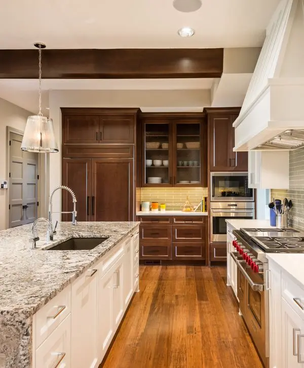 A traditional kitchen remodeling project in Union Beach, NJ, featuring custom dark wood cabinets, a large island with light granite countertops, stainless steel appliances, and warm hardwood floors.