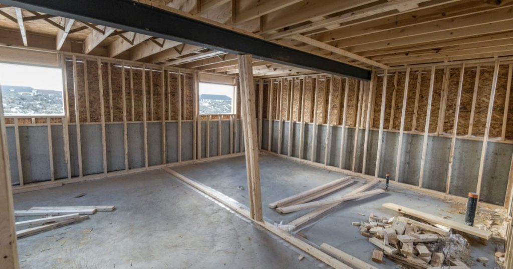 An unfinished basement interior showing newly installed wooden wall framing, a steel ceiling I-beam, and concrete floors, representing an ideal stage to address basement moisture in Matawan before drywall installation.