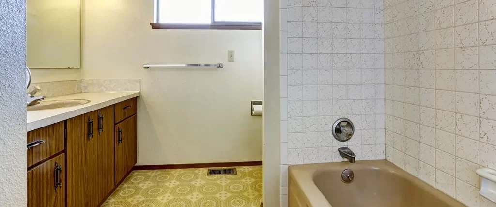 Outdated bathroom before remodel with vintage fixtures, tile surround, and aging vanity