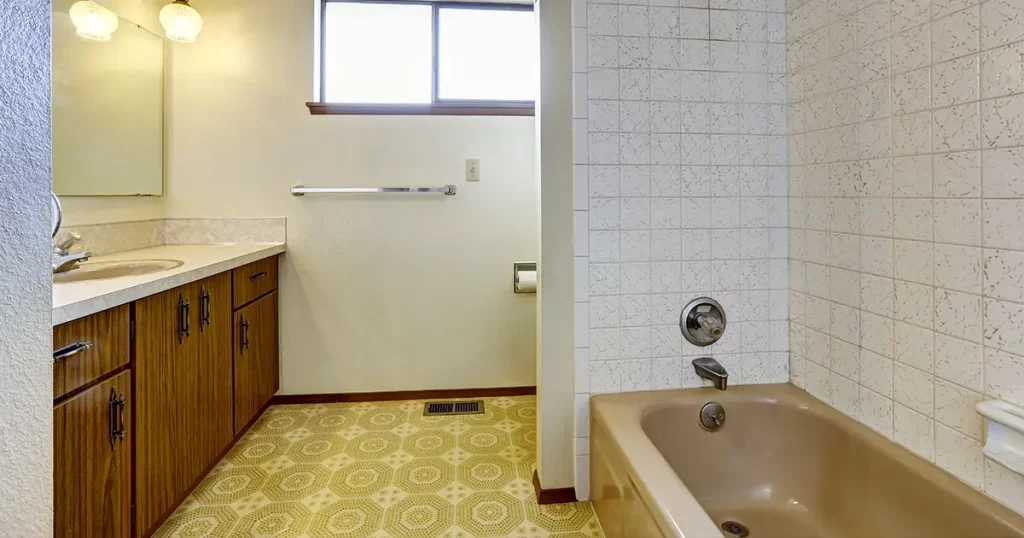 Outdated bathroom before remodel with vintage fixtures, tile surround, and aging vanity