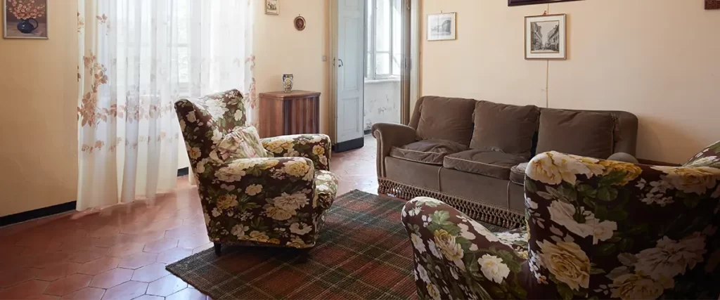 Outdated living room before renovation with worn finishes, aging furniture, and peeling walls
