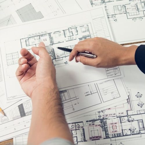 An architect pointing to specific details on Englishtown zoning codes blueprints during a project planning session.